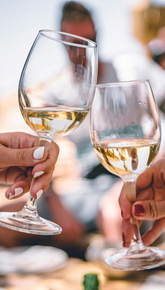 A photo of clinking glasses with white wine